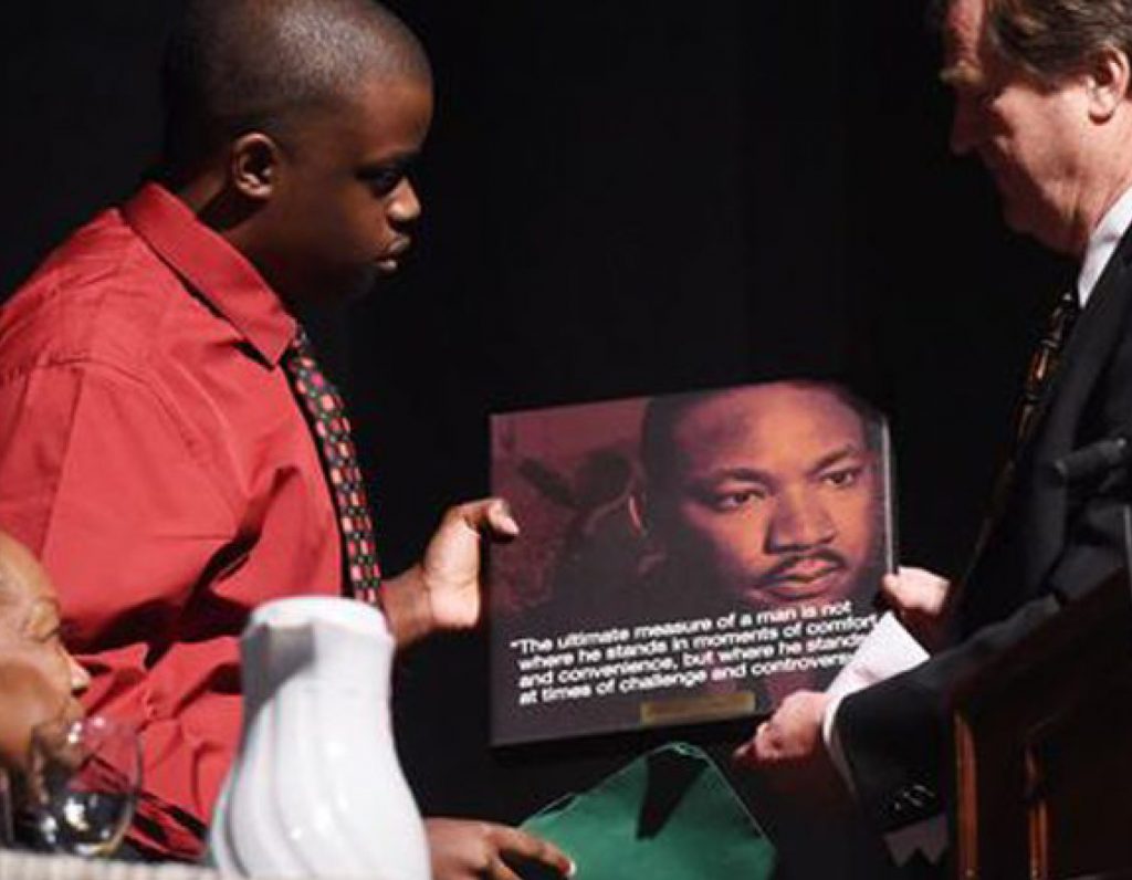 two people holding plaque with image of martyin luther king jr with a quote